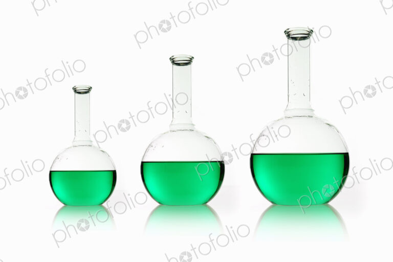 Three rounded shaped scientific chemical flasks holding green liquid, arranged in size…