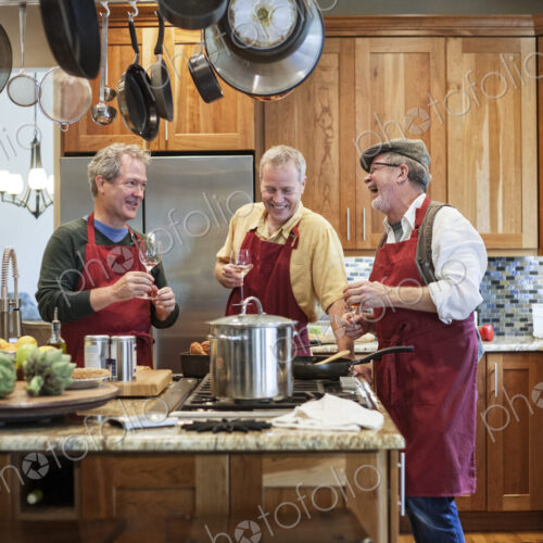 Three senior men friends cooking a meal in the kitchen.