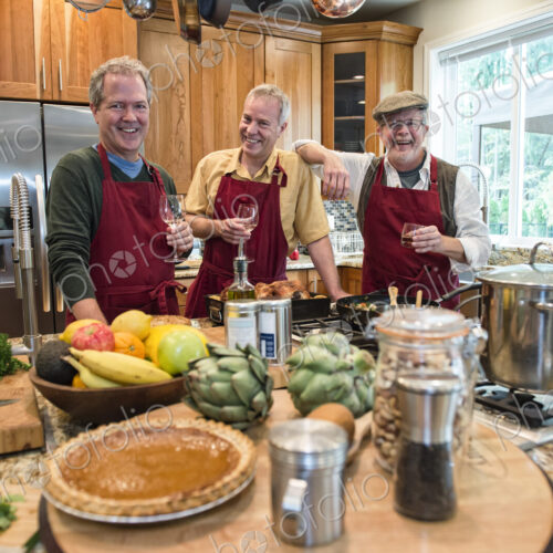 Three senior men friends cooking a meal in the kitchen.