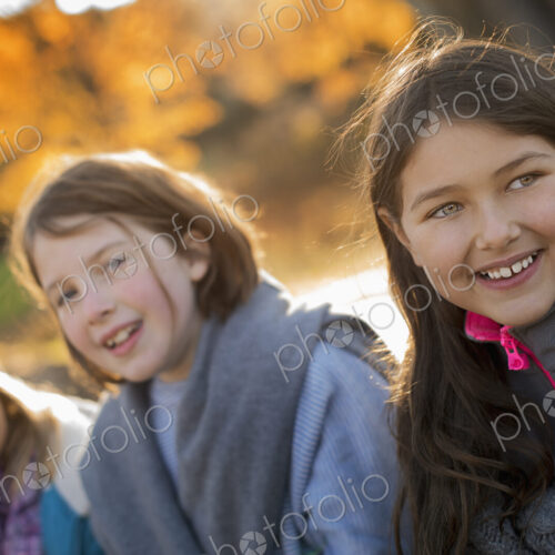Three young girls, children, outside in the fresh air. Autumn foliage.