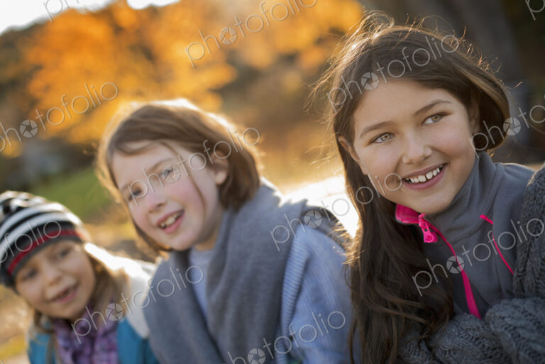 Three young girls, children, outside in the fresh air. Autumn foliage.