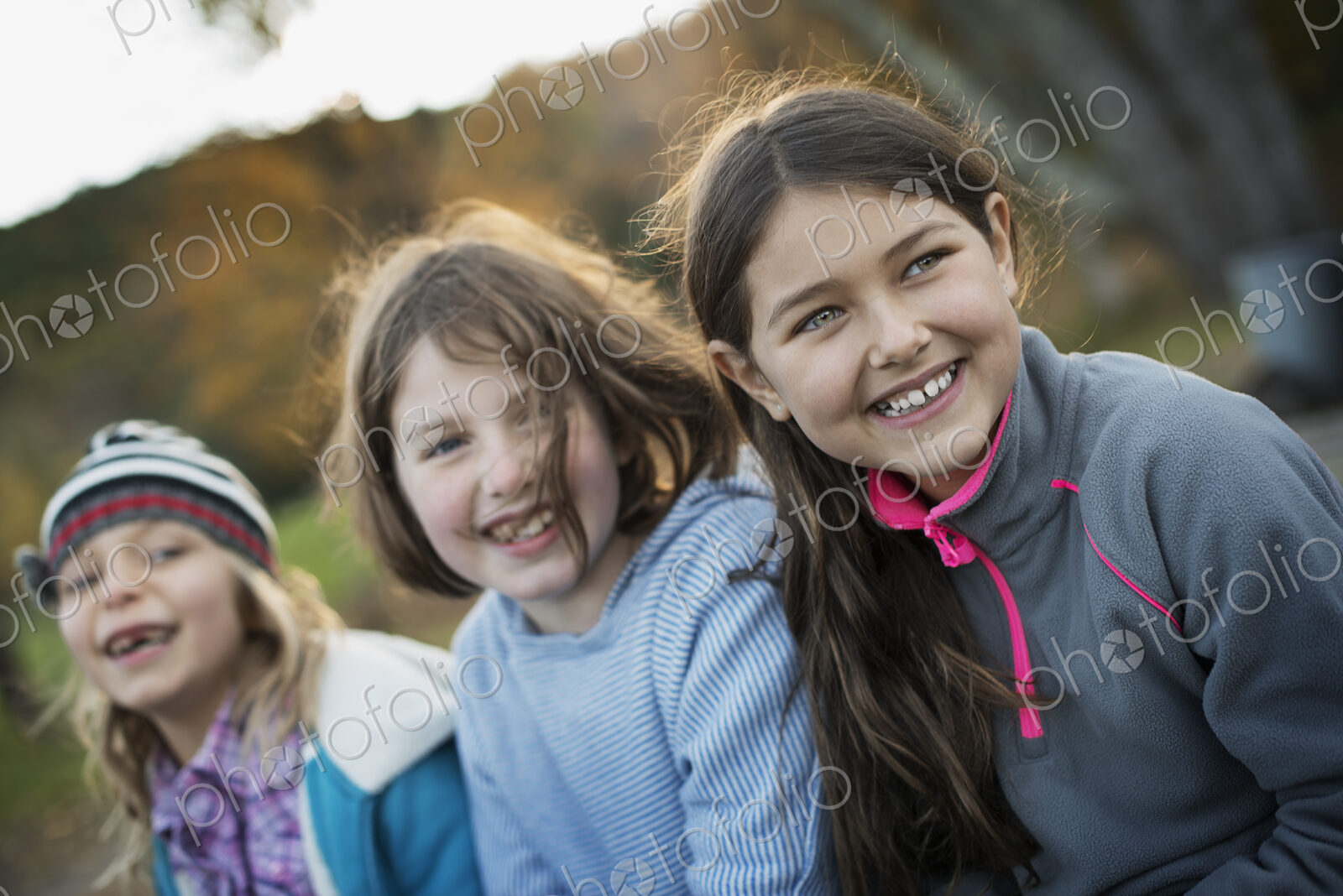 Three young girls, children, outside in the fresh air. Autumn foliage.