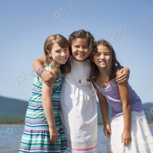 Three young girls, friends, hugging each other and smiling. Three young girls, friends, hugging each other and smiling.