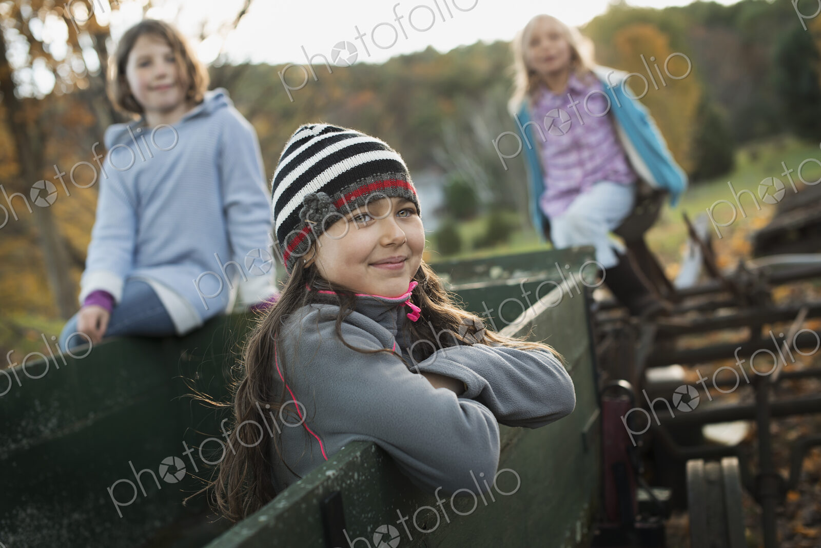 Three young girls out and about on the farm. On an old trailer.