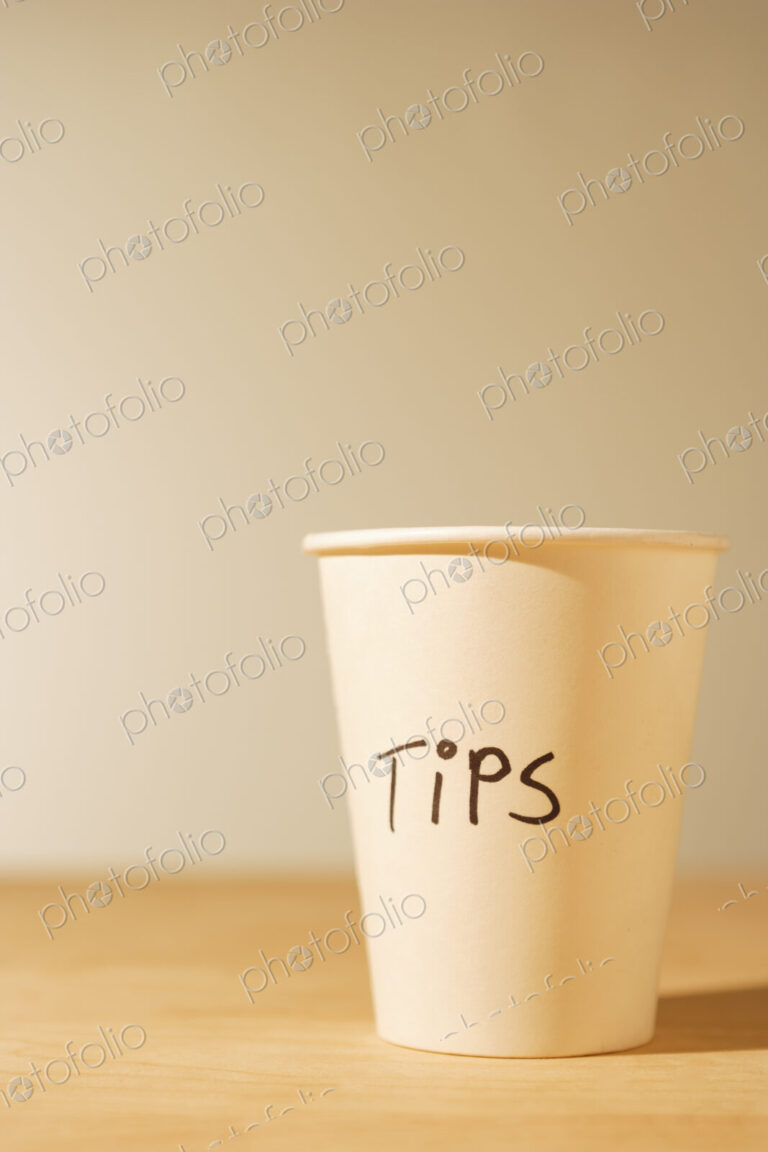 Tips cup, a white paper cup for gratuities on a table.