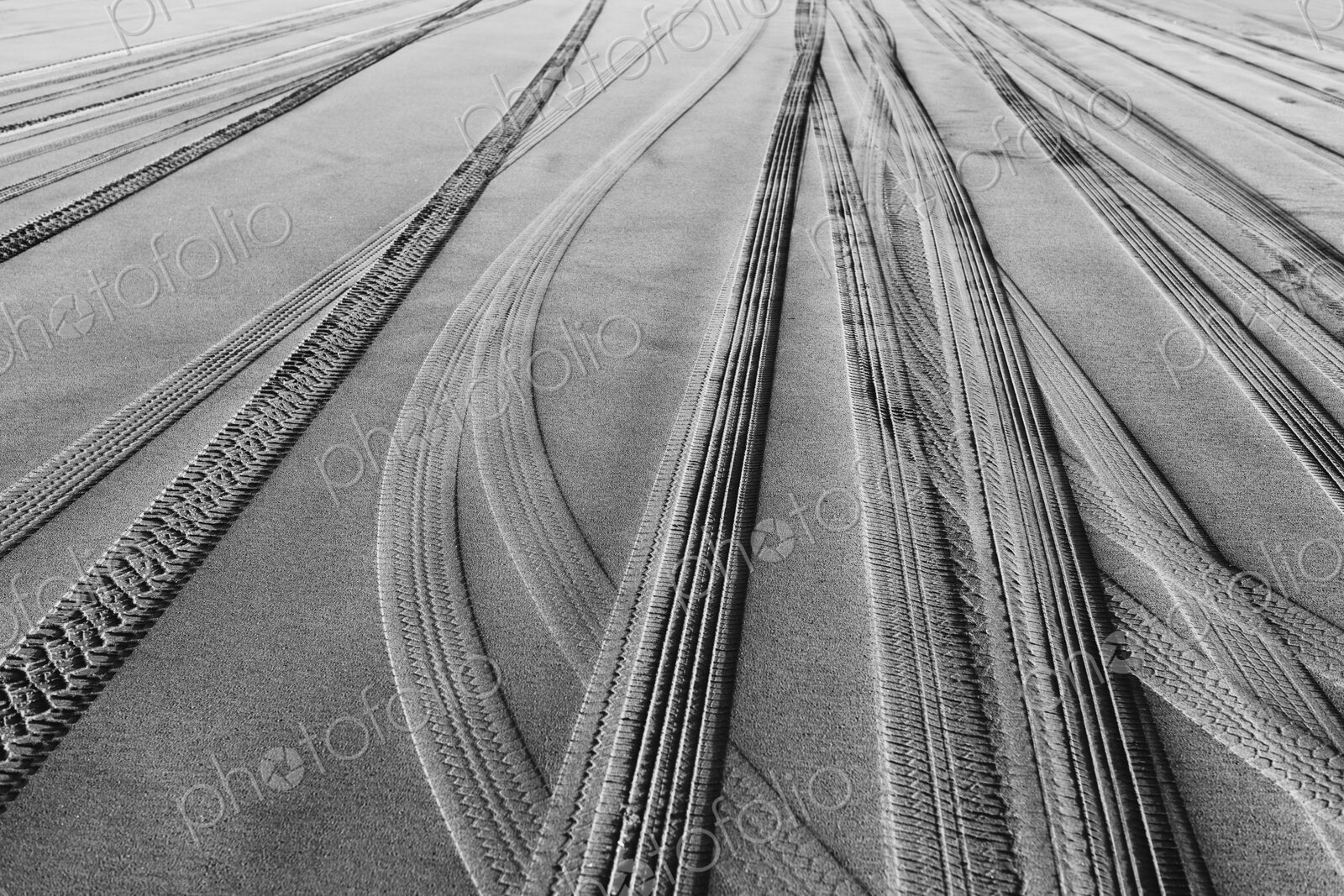 Tire tracks on the soft surface of sand on a beach.