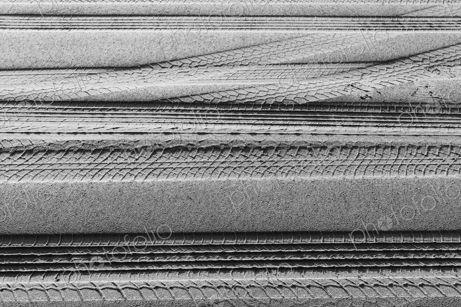 Tire tracks on the soft surface of sand on a beach.