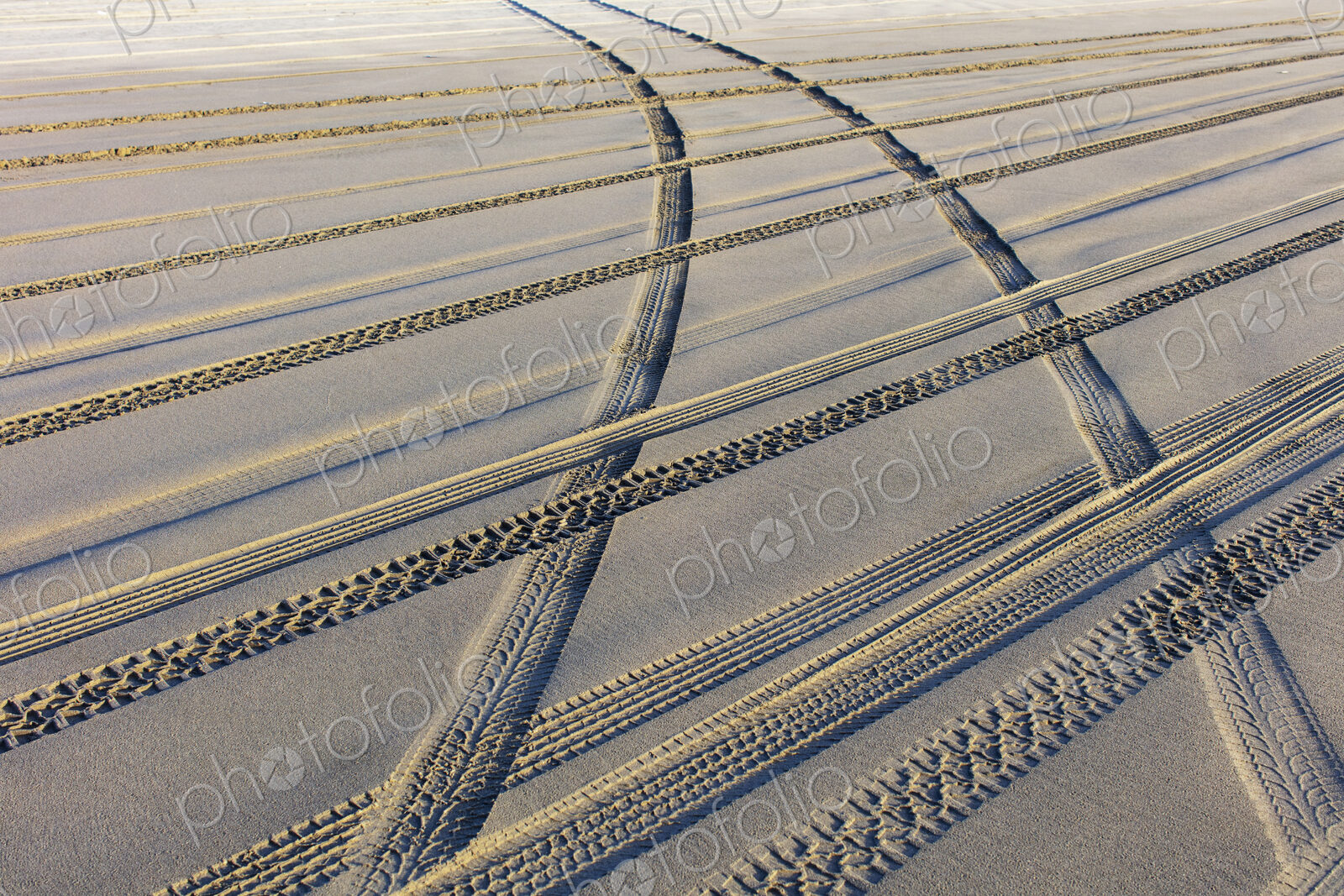 Tire tracks on the soft surface of sand on a beach.