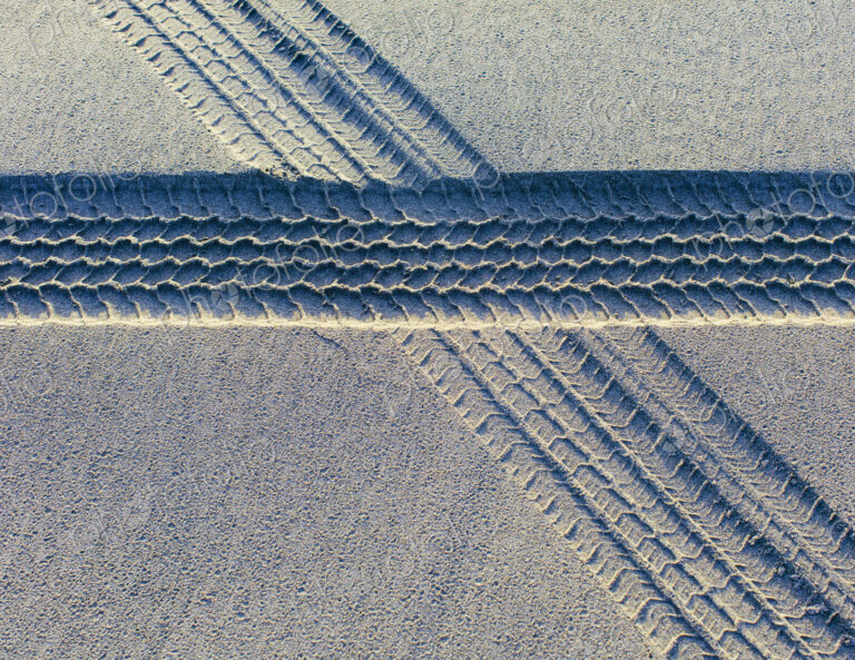 Tire tracks on the soft surface of sand on a beach.