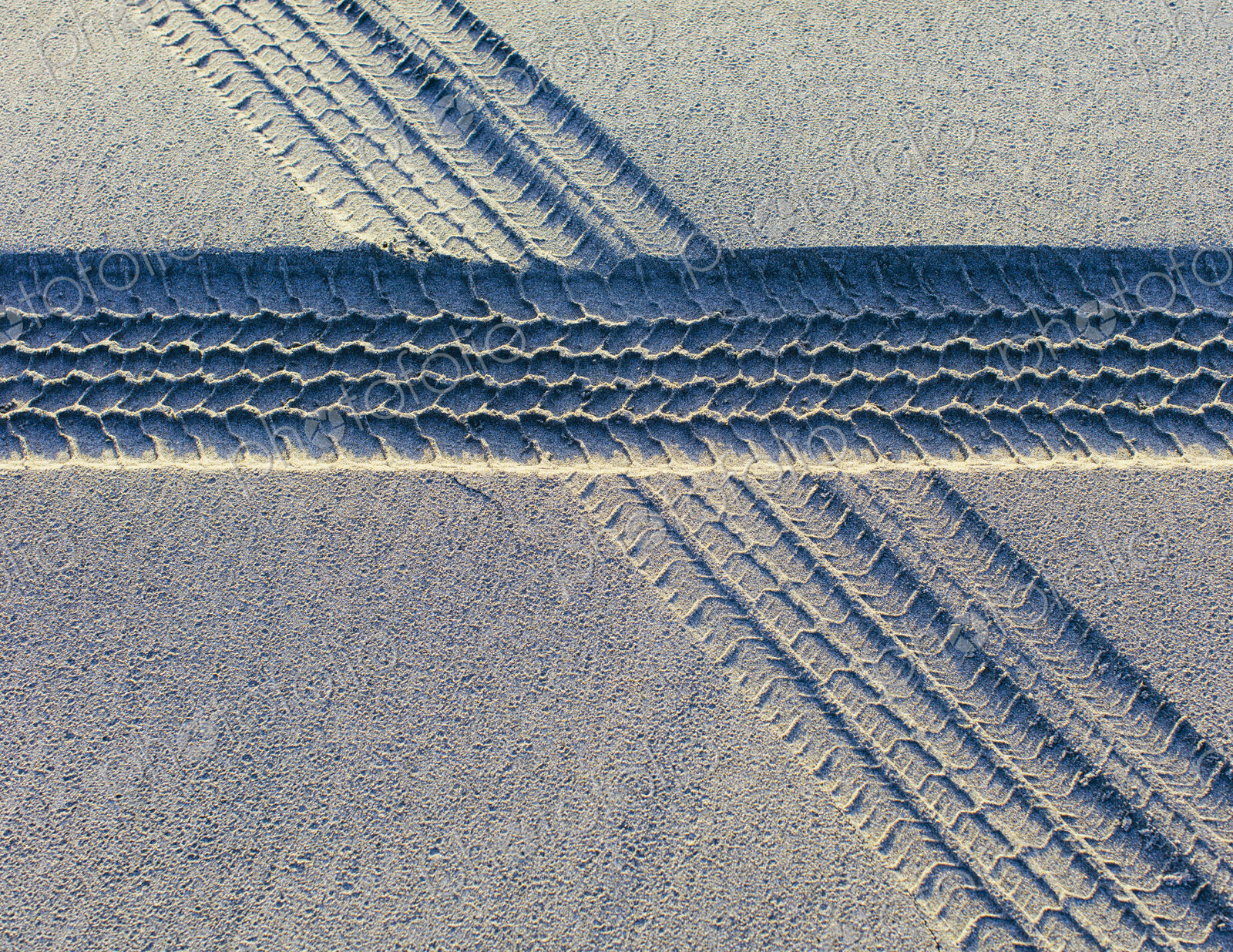 Tire tracks on the soft surface of sand on a beach.
