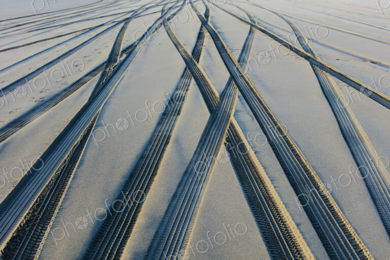 Tire tracks on the soft surface of sand on a beach.