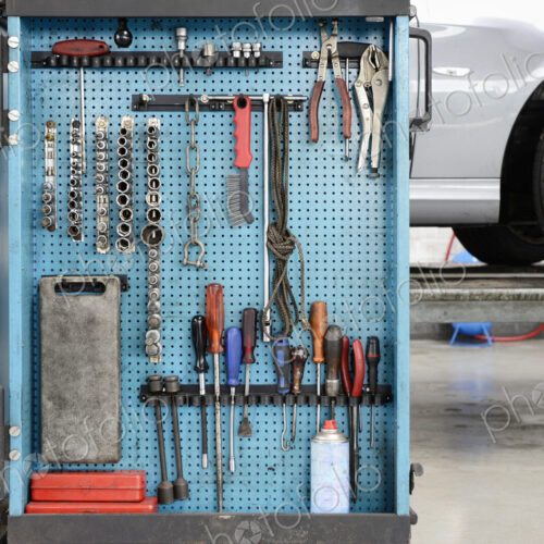 Tools on a blue board in a storage cabinet,organised in rows,at an auto repair shop. Tools on a blue board in a storage cabinet,organised in rows,at an auto repair shop.