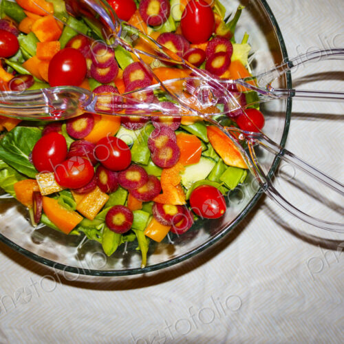 Top view of a mixed salad in a bowl with salad servers. Top view of a mixed salad in a bowl with salad servers.