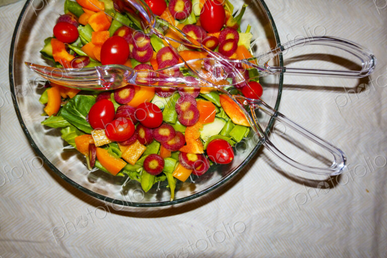 Top view of a mixed salad in a bowl with salad servers.
