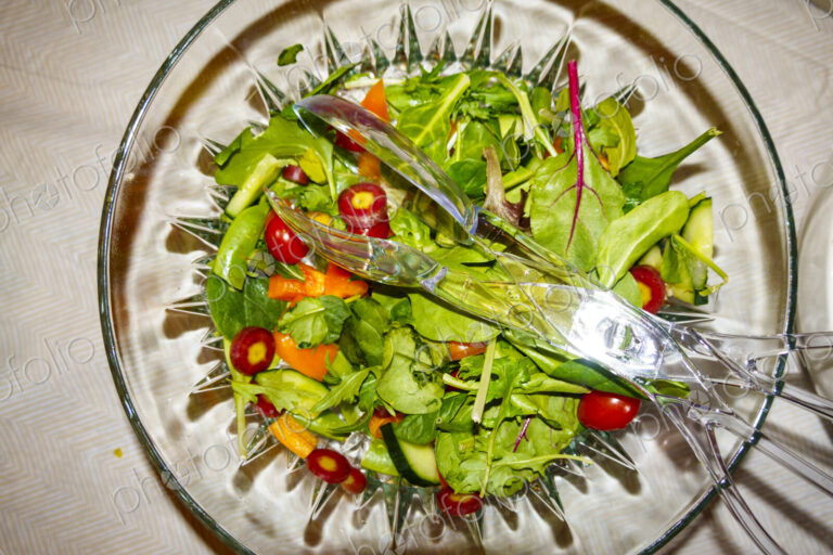 Top view of salad in a clear glass bowl fresh salad leaves and tomatoes.