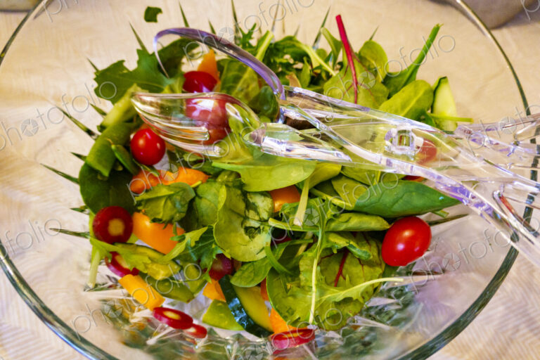 Top view of salad in a clear glass bowl fresh salad leaves and tomatoes.
