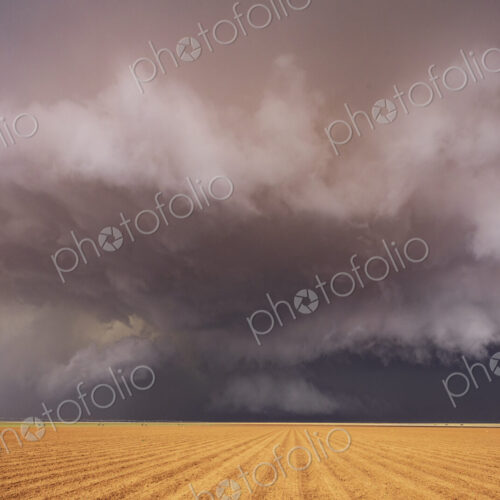 Tornado-Producing Supercell, clouds gathering above a cornfield, dark shapes on the…