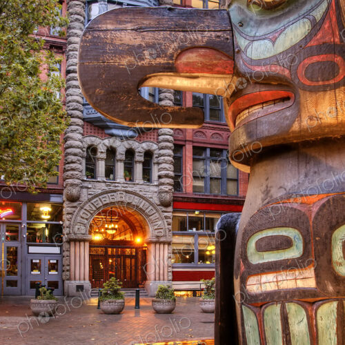 Totem pole on street with historic apartment building behind. Totem pole on street with historic apartment building behind.
