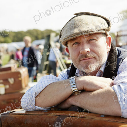 Trader resting leaning on a pile of cases at flea market