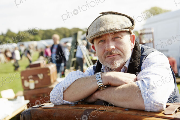 Trader resting leaning on a pile of cases at flea market