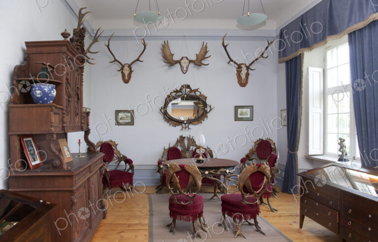Traditional furniture and hunting trophies, carved chest of drawers, wall plaques and…