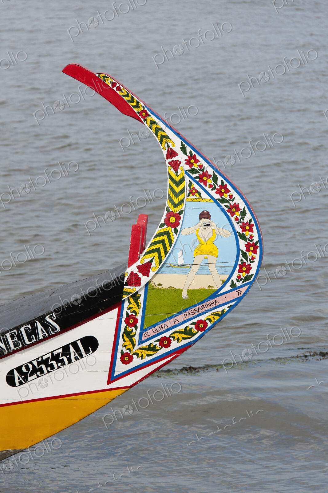Traditional moliceiro fishing boat with a high prow, painted in vivid colours and with…