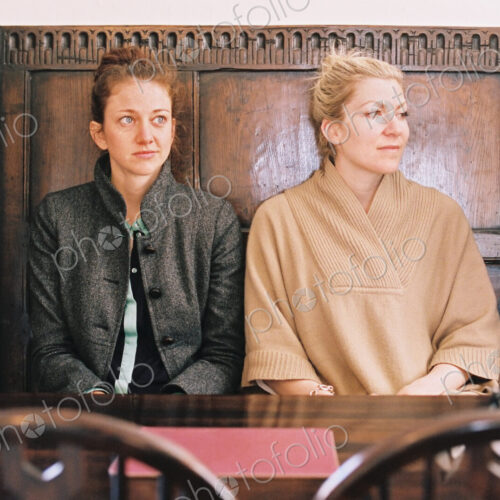 Traditional pub seat with a high back and curved sides. Two women sitting at a table. Traditional pub seat with a high back and curved sides. Two women sitting at a table.