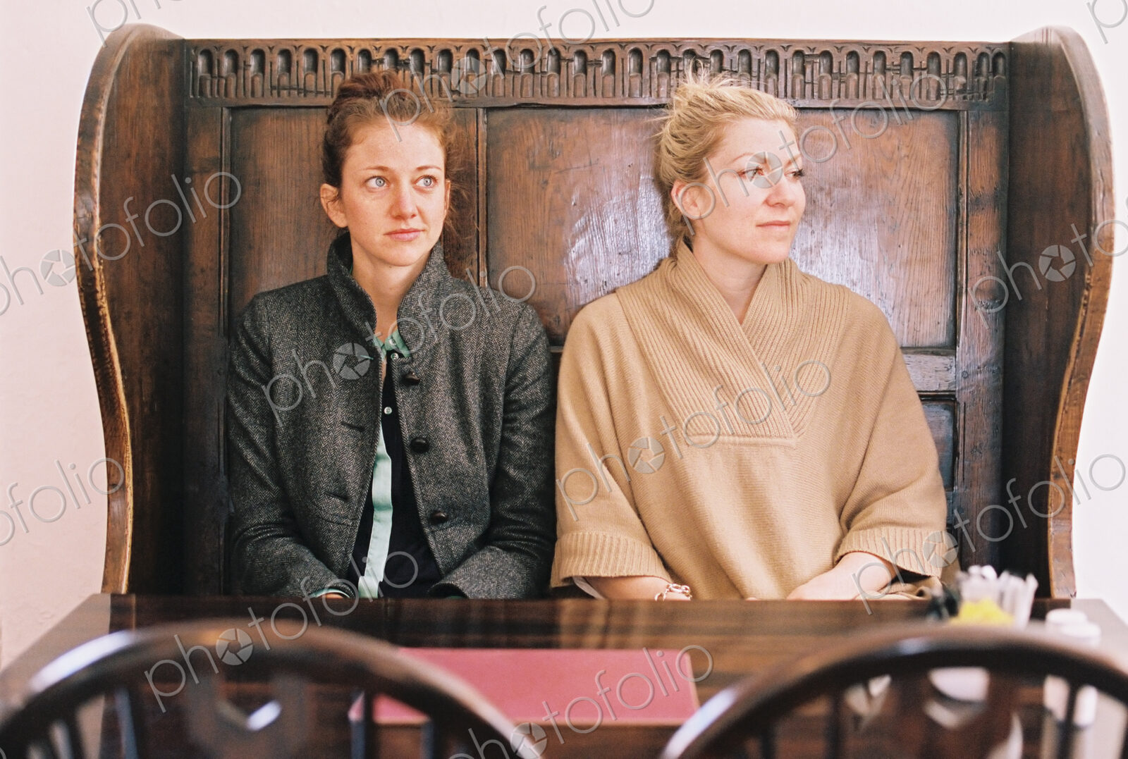 Traditional pub seat with a high back and curved sides. Two women sitting at a table.