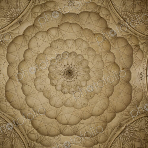 Traditional scalloped shaped patterns on a ceiling in concentric circles seen from…