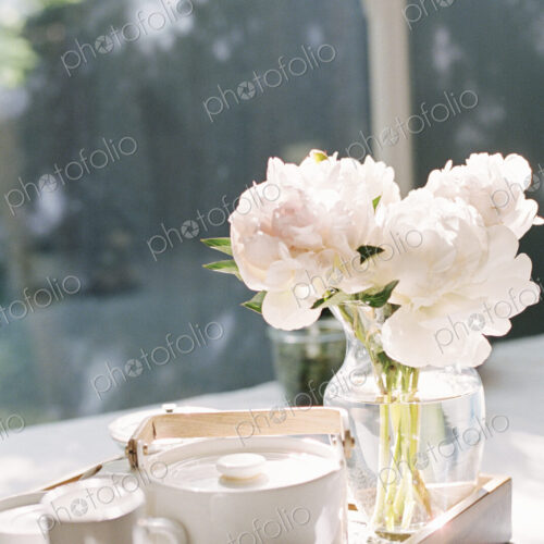 Tray with a teapot and a vase with white roses. Tray with a teapot and a vase with white roses.