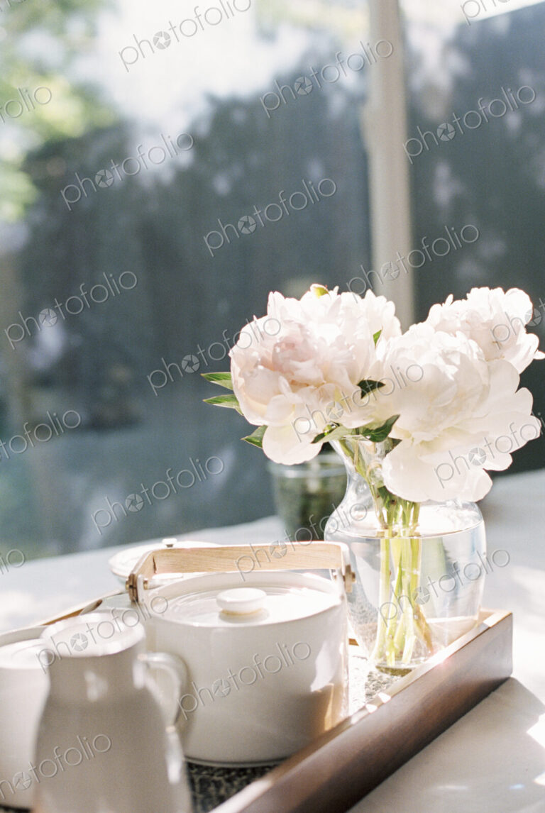 Tray with a teapot and a vase with white roses.