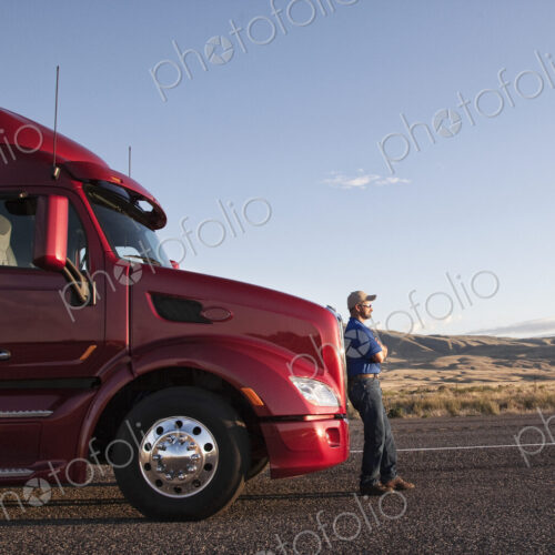 Truck driver leaning on the grill of his commercial truck. Truck driver leaning on the grill of his commercial truck.
