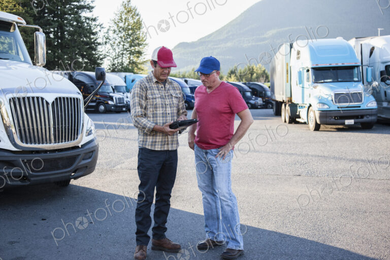 Truck driver team of caucasian drivers going over dispatch information in the parking…