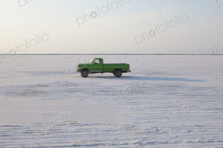 Truck driving on Bonneville Salt Flats, during Speed Week, dusk
