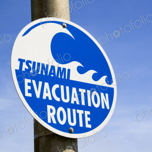 Tsunami Evacuation Route road sign, a graphic sign with lettering on a pole. Tsunami Evacuation Route road sign, a graphic sign with lettering on a pole.