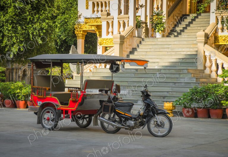 Tuk tuk taxi on street outside grand staircase to hotel or resort.