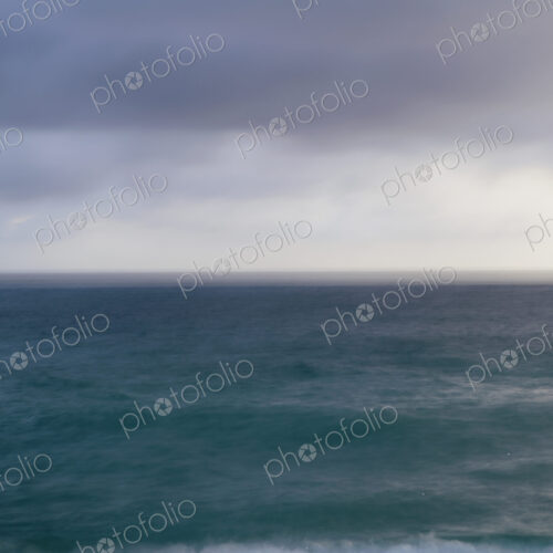 Turquoise ocean surface under a grey stormy sky. Turquoise ocean surface under a grey stormy sky.
