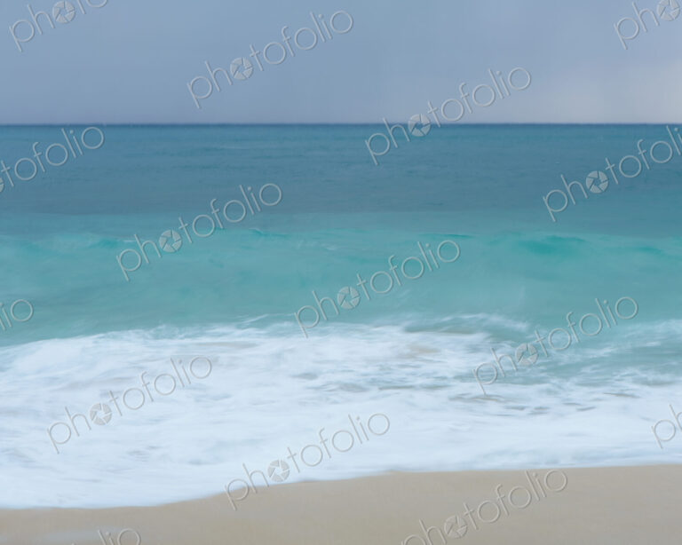 Turquoise sea, waves breaking on a sandy beach.