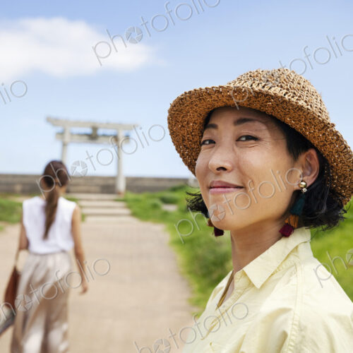 Two Japanese woman wearing hats standing on a path, Shinto shrine in the background. Two Japanese woman wearing hats standing on a path, Shinto shrine in the background.