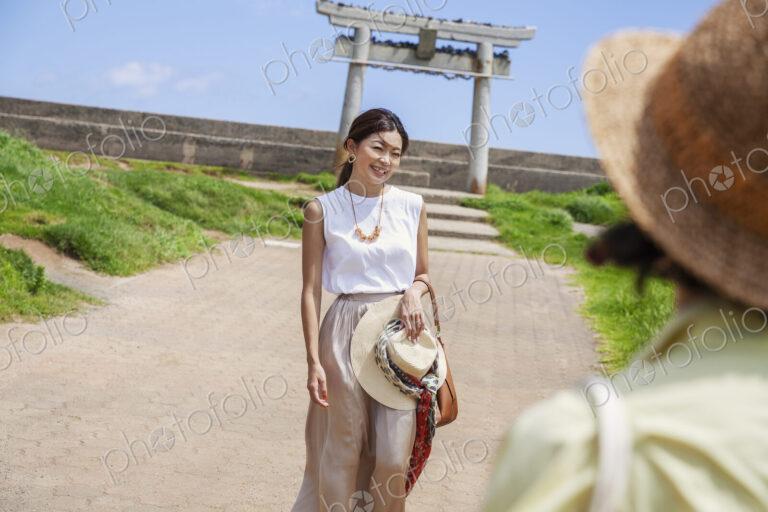 Two Japanese woman wearing hats standing on a path, taking picture.