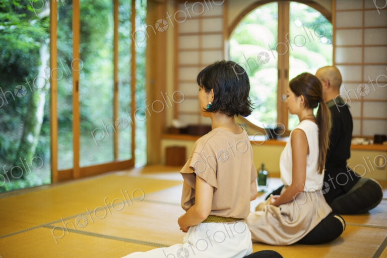 Two Japanese women and Buddhist priest kneeling in Buddhist temple, praying.