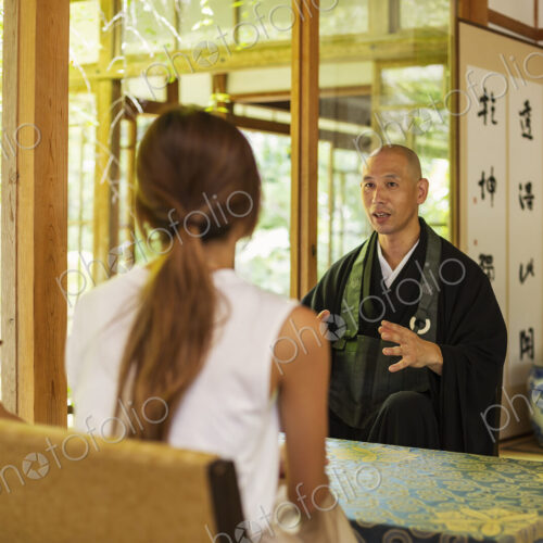 Two Japanese women and Buddhist priest kneeling in Buddhist temple, talking. Two Japanese women and Buddhist priest kneeling in Buddhist temple, talking.