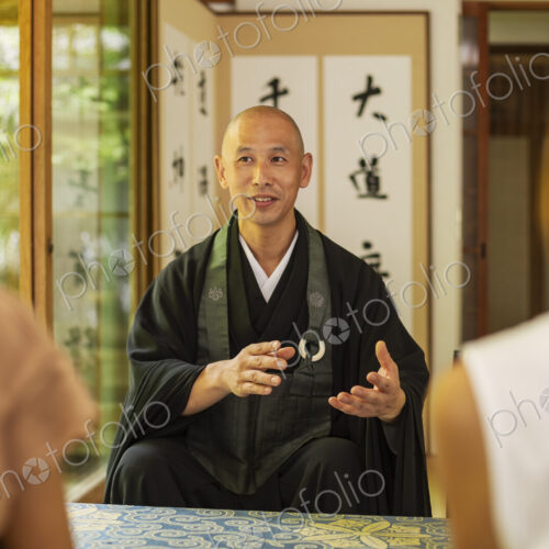 Two Japanese women and Buddhist priest kneeling in Buddhist temple, talking. Two Japanese women and Buddhist priest kneeling in Buddhist temple, talking.