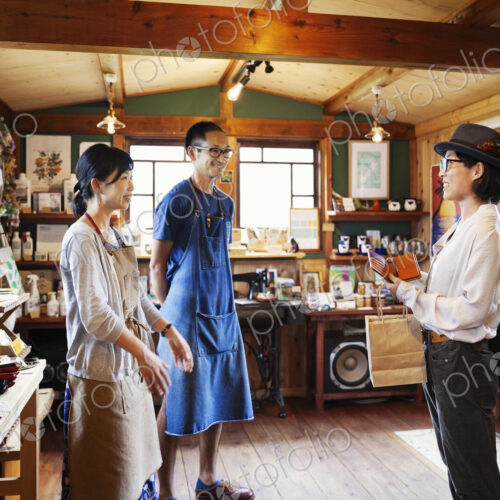 Two Japanese women and man standing in a leather shop. Two Japanese women and man standing in a leather shop.