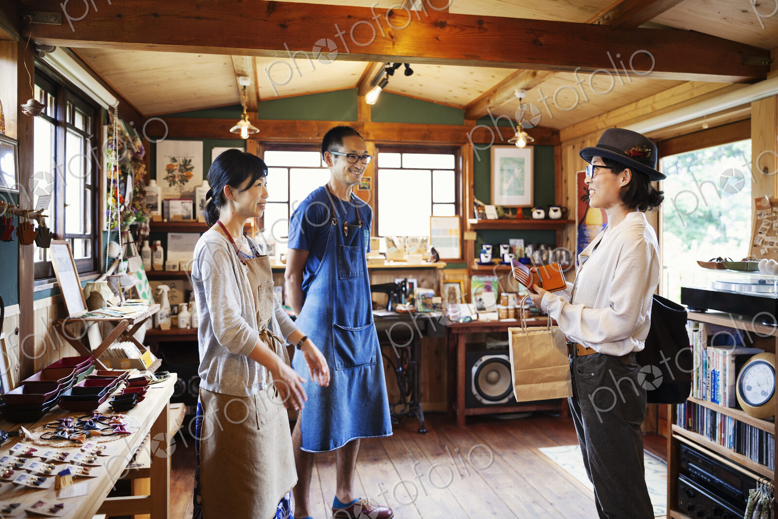 Two Japanese women and man standing in a leather shop.