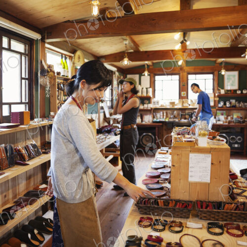 Two Japanese women and man standing in a leather shop.