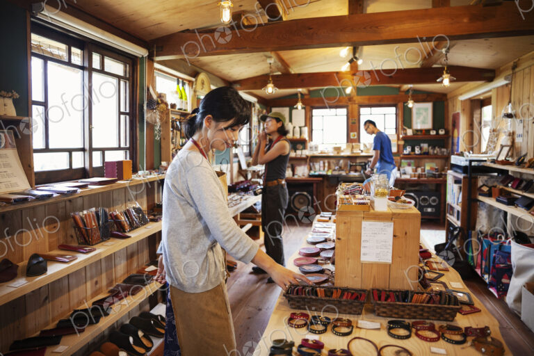 Two Japanese women and man standing in a leather shop.