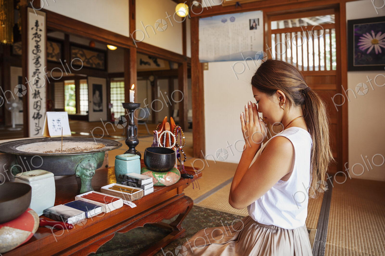 Two Japanese women kneeling in Buddhist temple, praying.