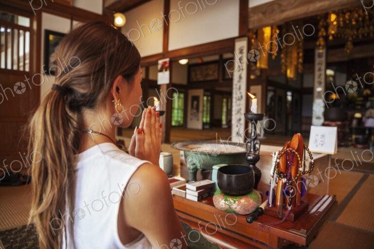 Two Japanese women kneeling in Buddhist temple, praying.