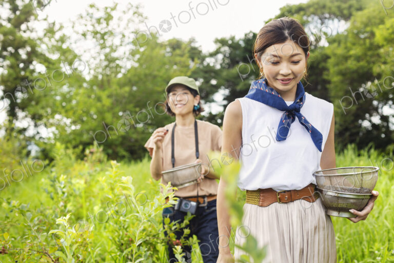 Two Japanese women picking berries in a field.